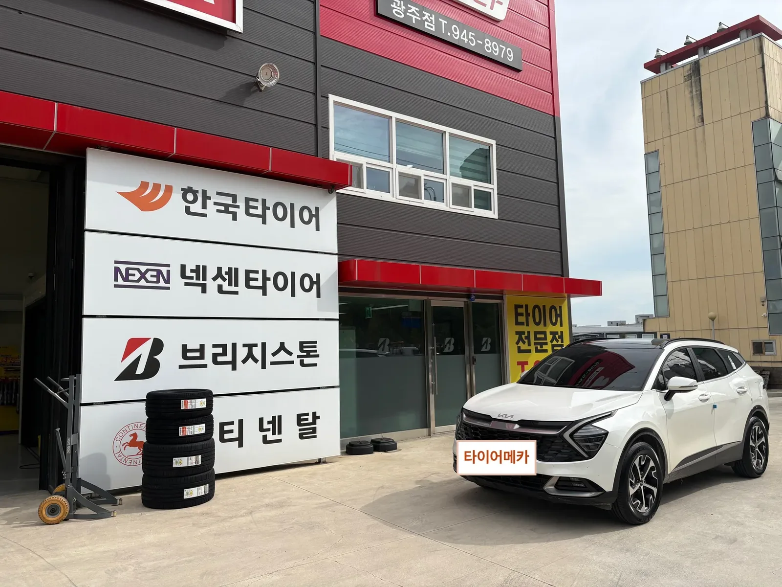 기아 스포티지 235/60R18 매장 간판 앞에 세워 둔 기아 스포티지와 새 타이어 4본